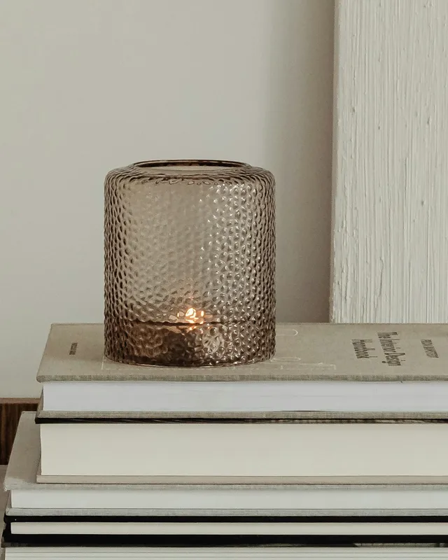 An amber glass tealight holder in a softly lit still-life arrangement.